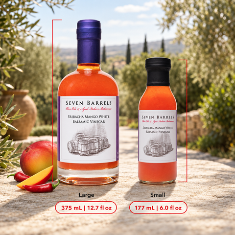 Two bottles of Seven Barrels Srubacha Mango White Balsamic Vinegar shown on a stone surface outdoors, with a large bottle labeled Large and a smaller bottle labeled Small. Red measurement lines and text indicate the sizes and volumes.