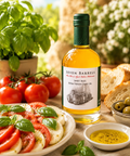 Seven Barrels Sweet Basil Extra Virgin Olive Oil served with fresh caprese salad, basil leaves, tomatoes, mozzarella, olives, and artisan bread.